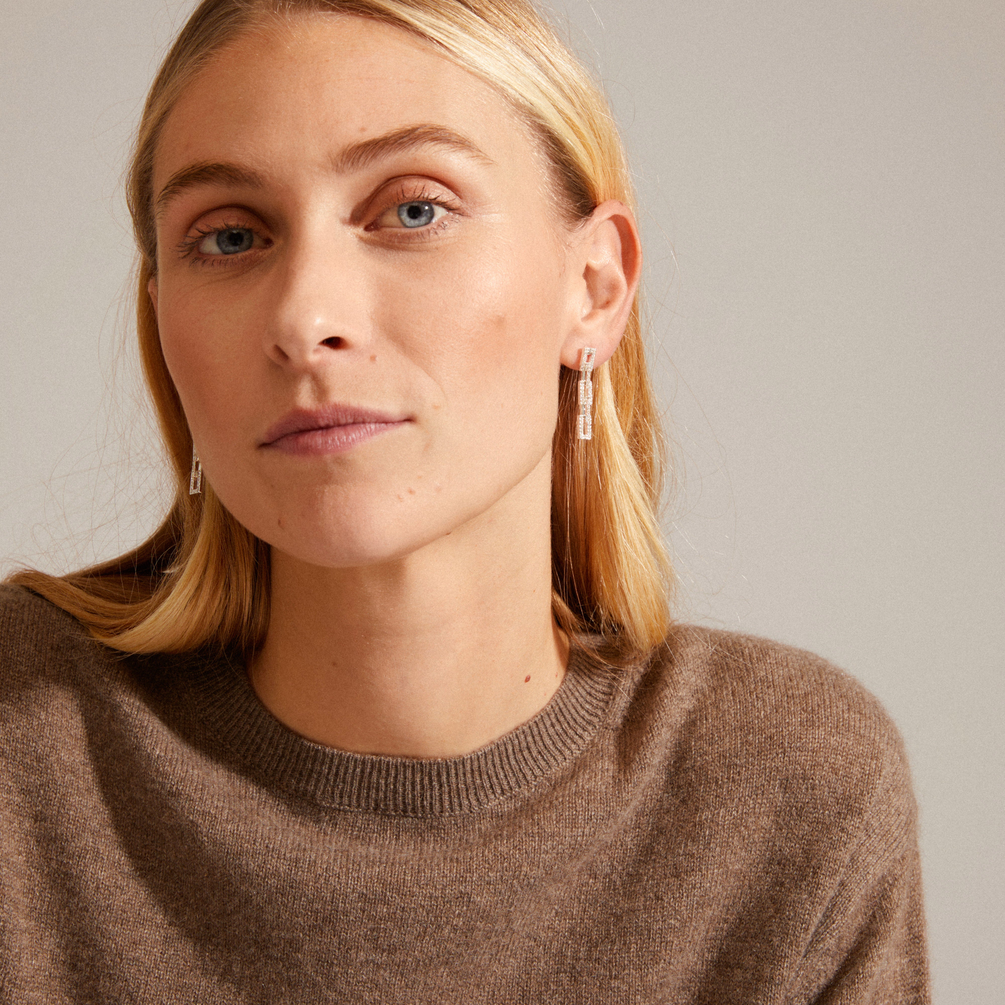 COBY crystal earrings silver-plated with a retro flair, featuring sparkling Preciosa crystals, worn by a woman in a close-up portrait.