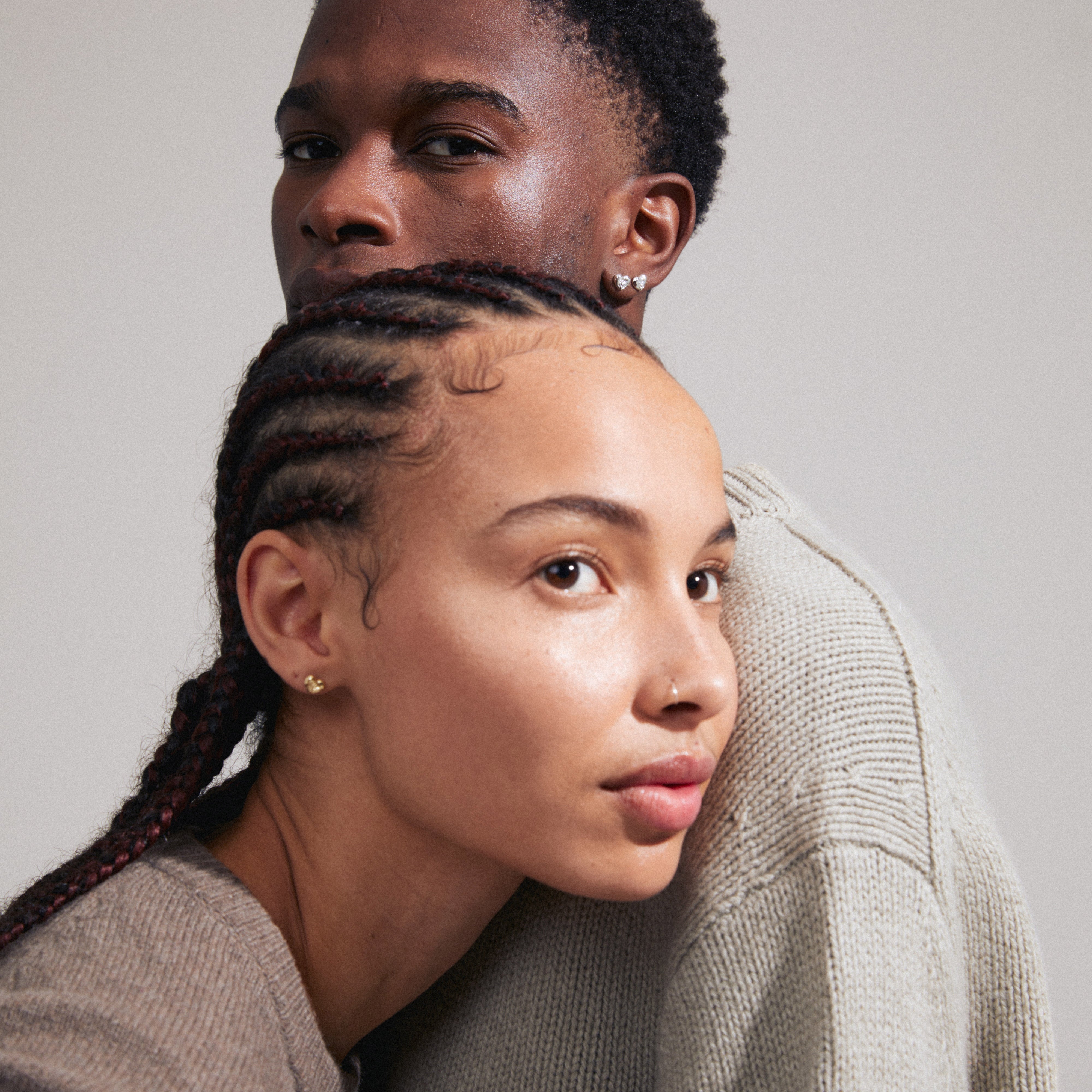 Man and woman showcasing ARLET gold-plated heart stud earrings, highlighting their versatile, rustic design ideal for gifting or personal style.