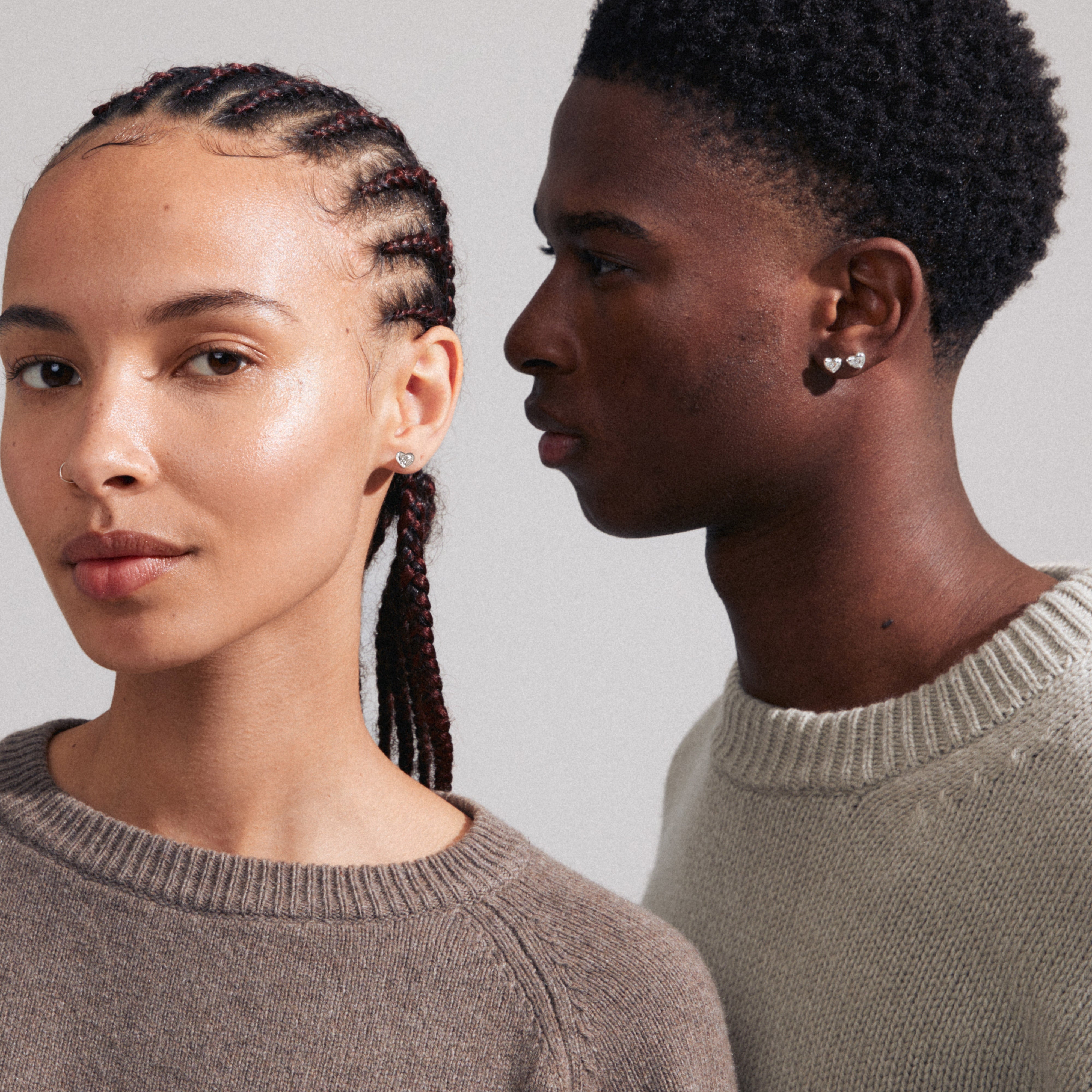 A man and woman wear ARLET earrings, silver-plated heart studs by Pilgrim, showcasing their rustic yet clean design, perfect for any style.