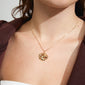 Woman wearing LUCA necklace gold-plated with a distinctive melting-shaped pendant, showcasing Pilgrim's eco-friendly, stylish Danish design. Perfect for adding a personal touch to outfits.