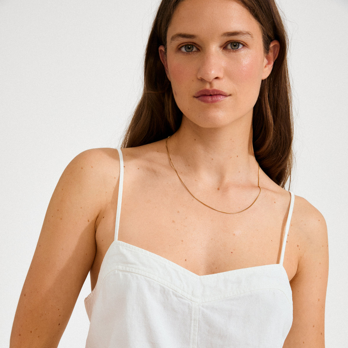 Young woman wearing a NANCY necklace 50 cm gold-plated, showcasing its minimalist elegance against a simple backdrop, perfect for layering or standalone style.