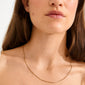 Close-up of a woman's neck wearing the NANCY necklace, a 50 cm gold-plated venetian chain by Pilgrim, elegantly draping along her collarbones.
