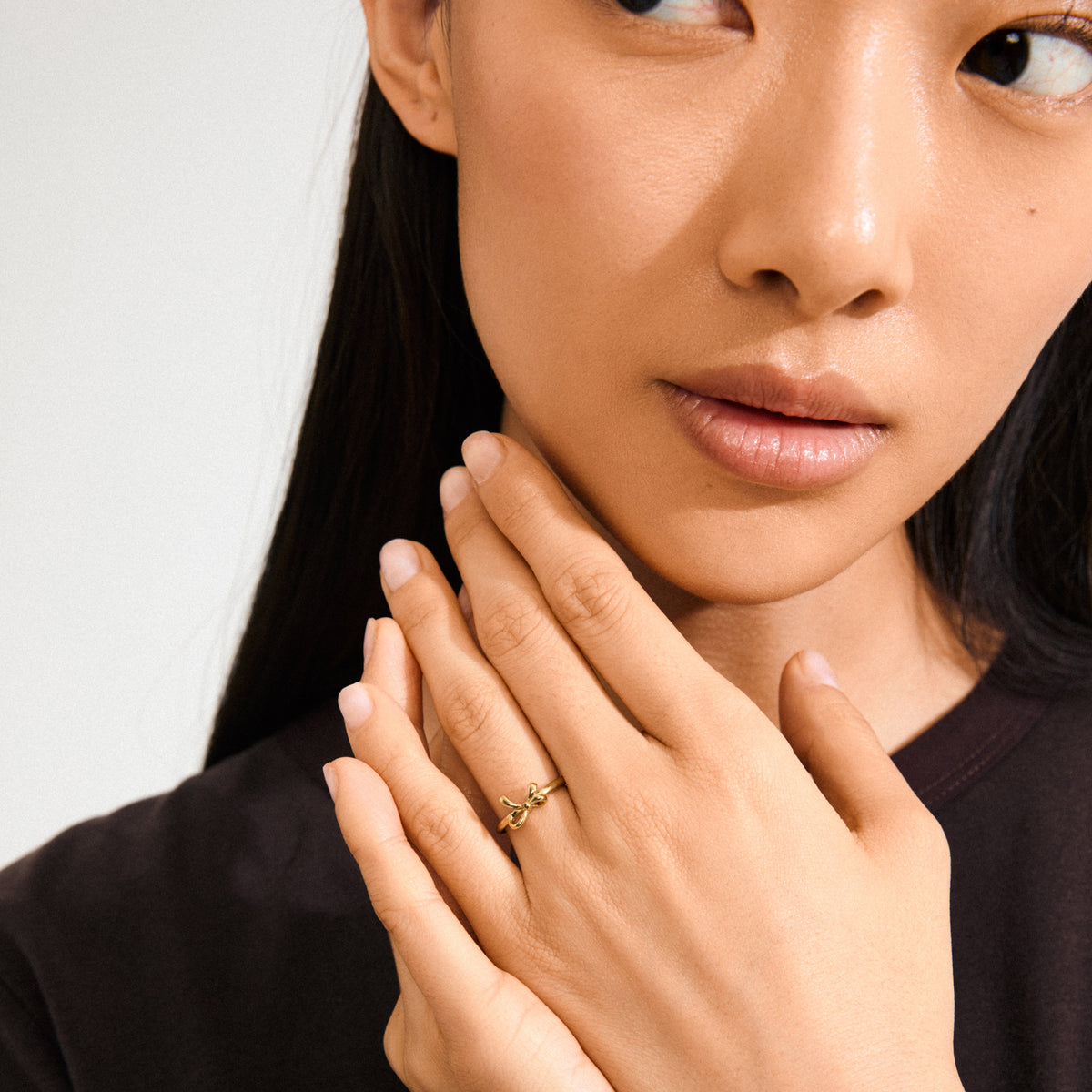 LULU bow stack ring gold-plated on a woman's hand, highlighting its sleek design perfect for layering with other Pilgrim rings.