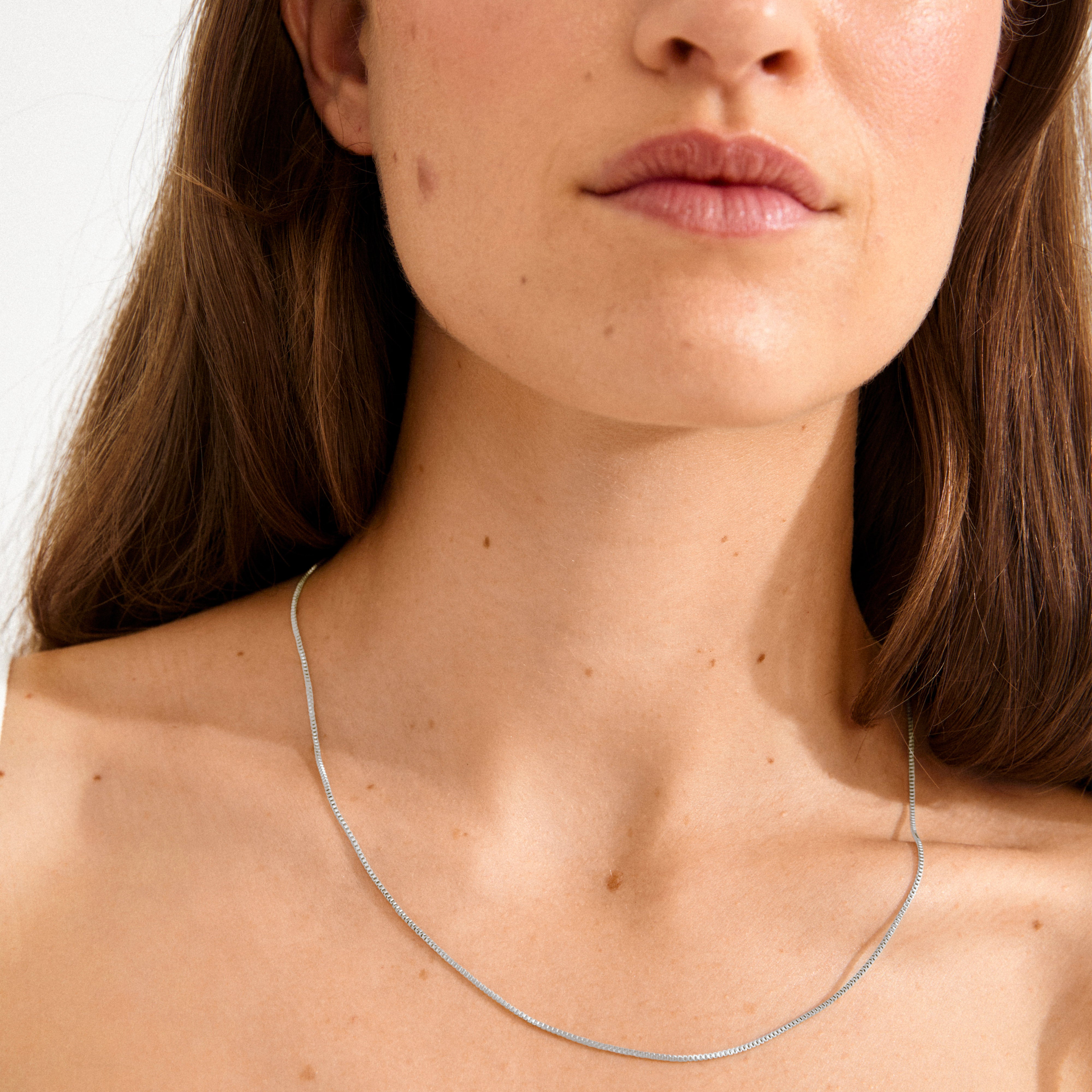 Close-up of a person wearing the NANCY necklace 50 cm silver-plated, showcasing its simple, stylish design, perfect for layering or adding a pendant.