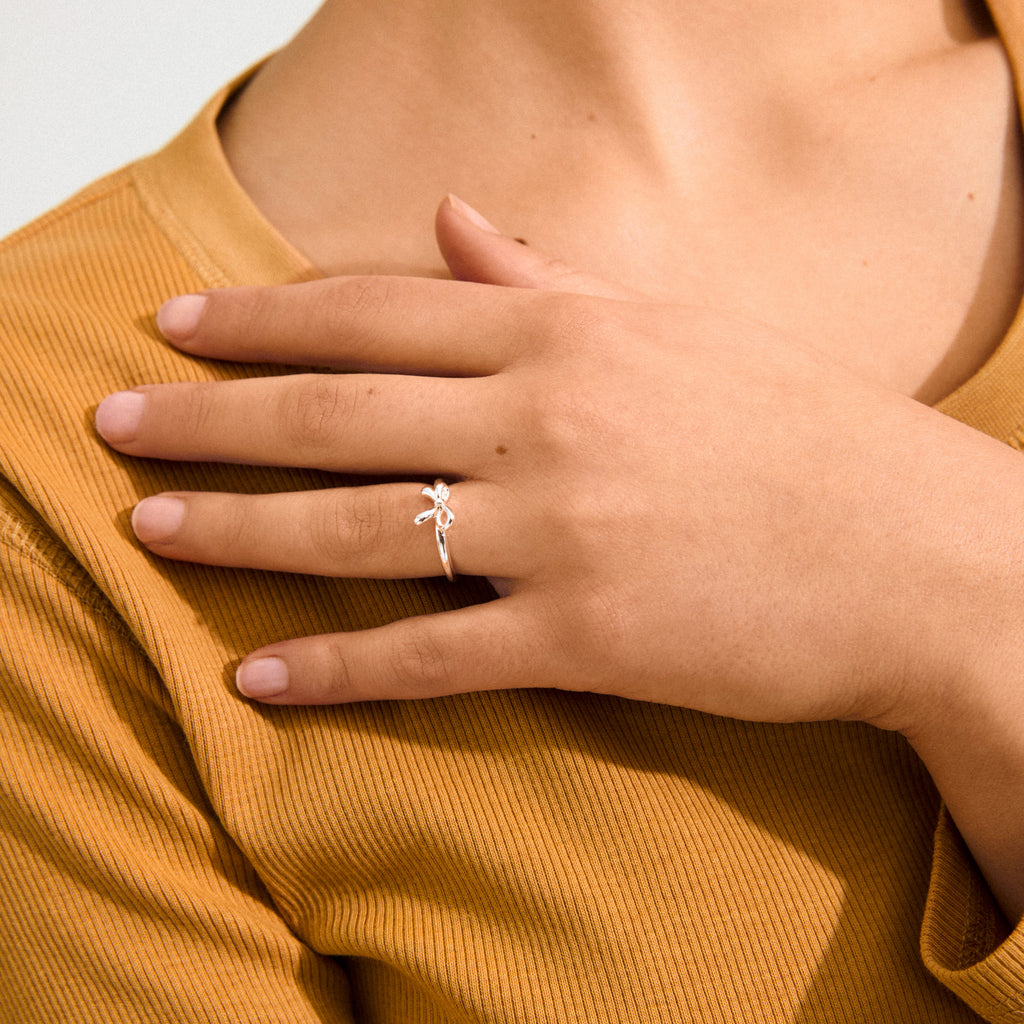 Silver-plated LULU bow stack ring on finger, highlighting its sleek, romantic design. Perfect for layering with Pilgrim's jewelry collection.