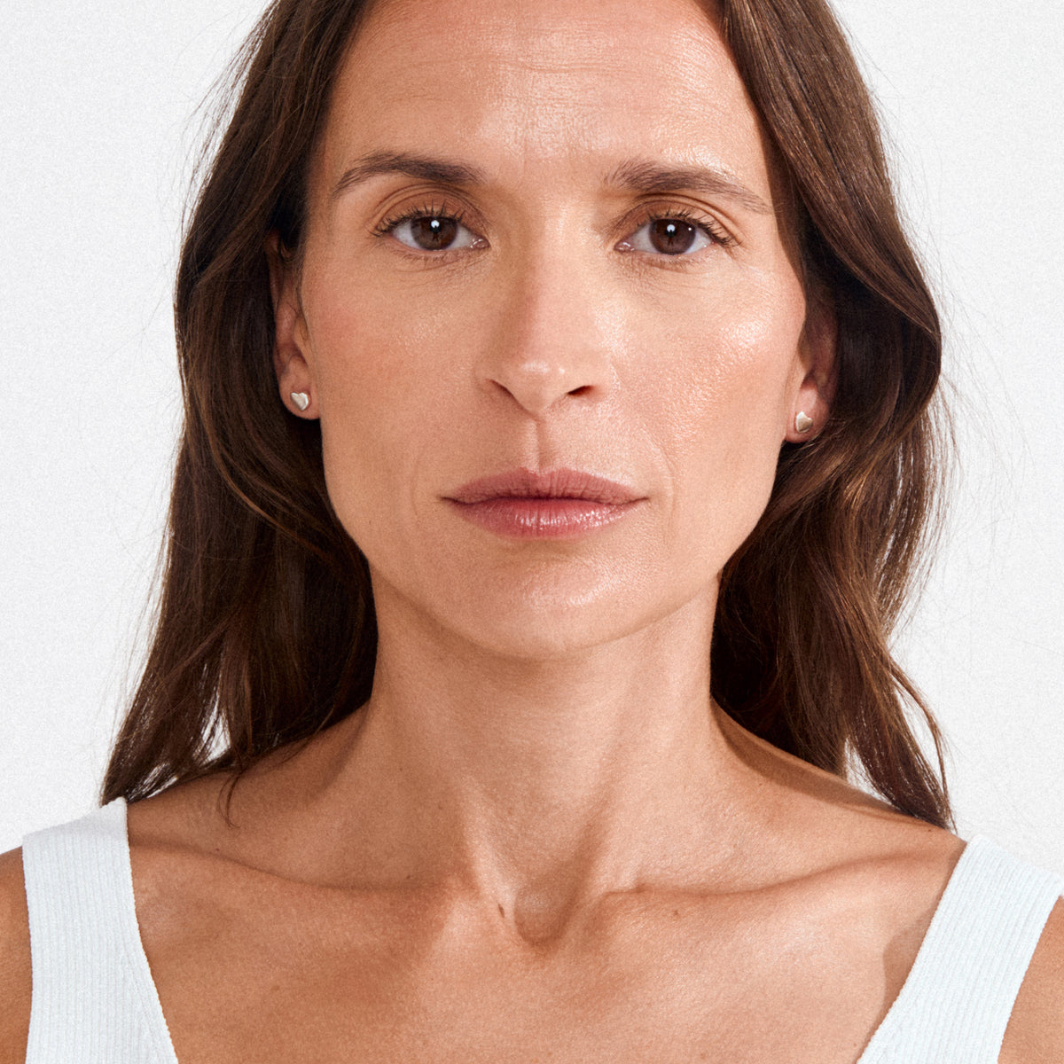 Close-up of a woman wearing Pilgrim's ARIN silver-plated heart-shaped stud earrings, highlighting their elegant simplicity and soft romantic vibe.
