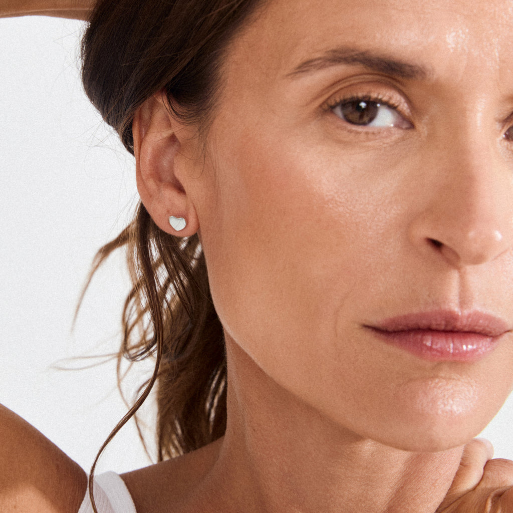 Close-up of woman’s ear wearing Pilgrim’s silver-plated ARIN heart-shaped stud earring, embodying romantic, minimalist style with a touch of elegant simplicity.