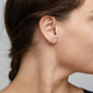Close-up of EDIE crystal heart earrings, gold-plated, worn on woman's ear. These delicate studs feature sparkling crystals, adding a romantic touch to any outfit.