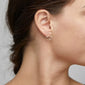 Close-up of DEBRA earrings, gold-plated with an artistic smiling face design, worn on a woman's ear, showcasing unique style and creativity.
