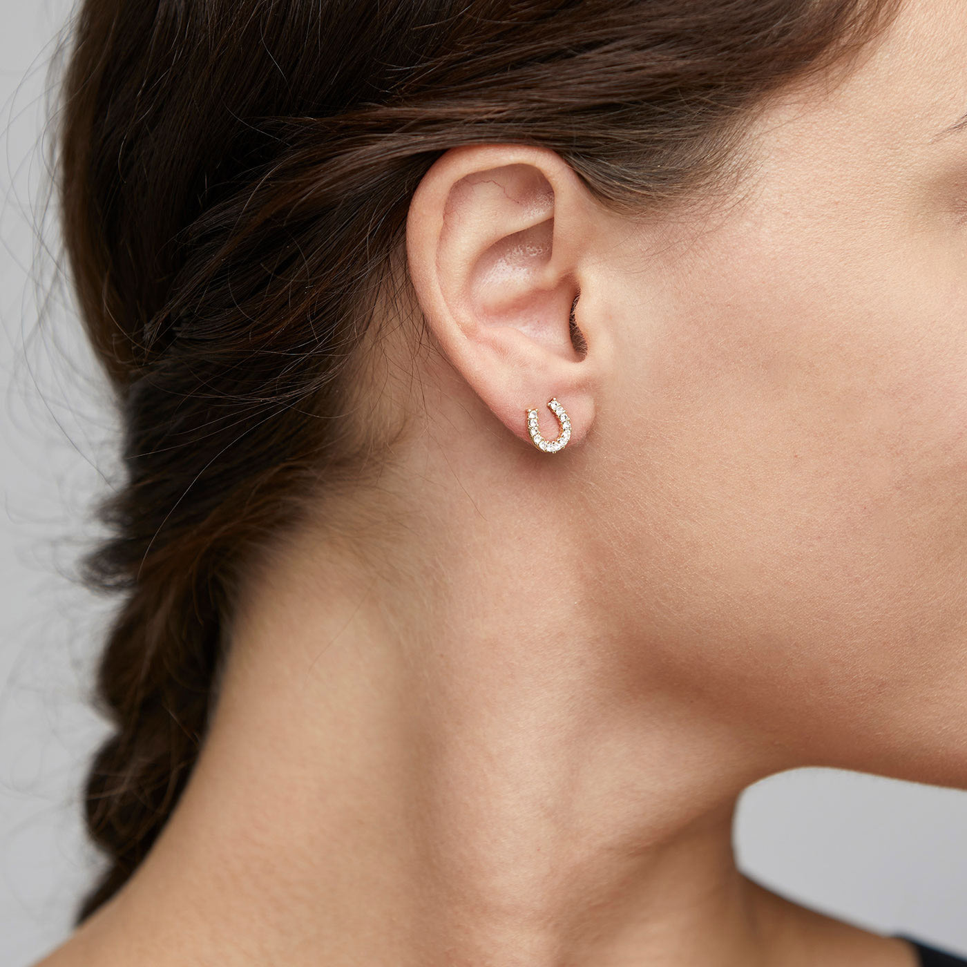 LEANNA good luck crystal earrings gold-plated, shaped like horseshoes, sparkle with polished sides and crystals, capturing light beautifully on a woman's ear.