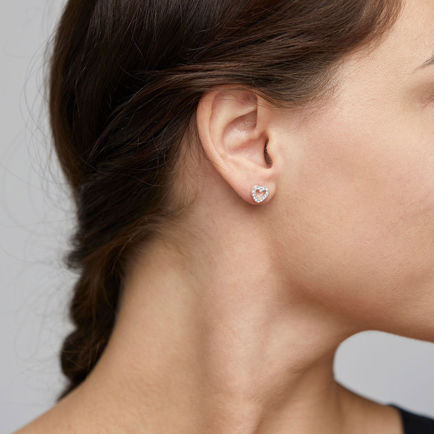 EDIE crystal heart earrings silver-plated adorn a woman's ear, showcasing their delicate heart shape and sparkling crystals that enhance a chic, romantic look.