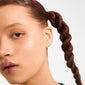 EDIE crystal heart earrings silver-plated, worn by a young person, featuring sparkling stones on a heart-shaped stud, complementing natural makeup and a thick braid.