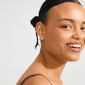 Young woman wearing LEANNA good luck crystal earrings, silver-plated horseshoe studs with sparkling crystals, styled to enhance natural beauty and capture light.