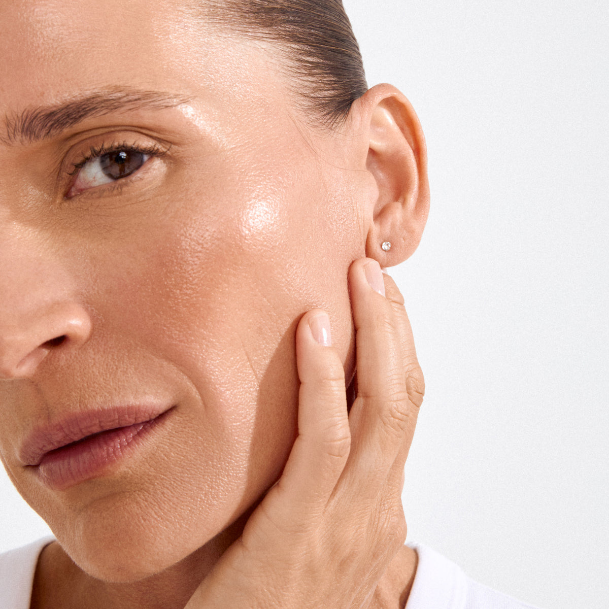 Close-up of a woman wearing SYLVIE small crystal stud earrings in gold-plated setting, highlighting the minimalist and elegant design perfect for everyday wear.