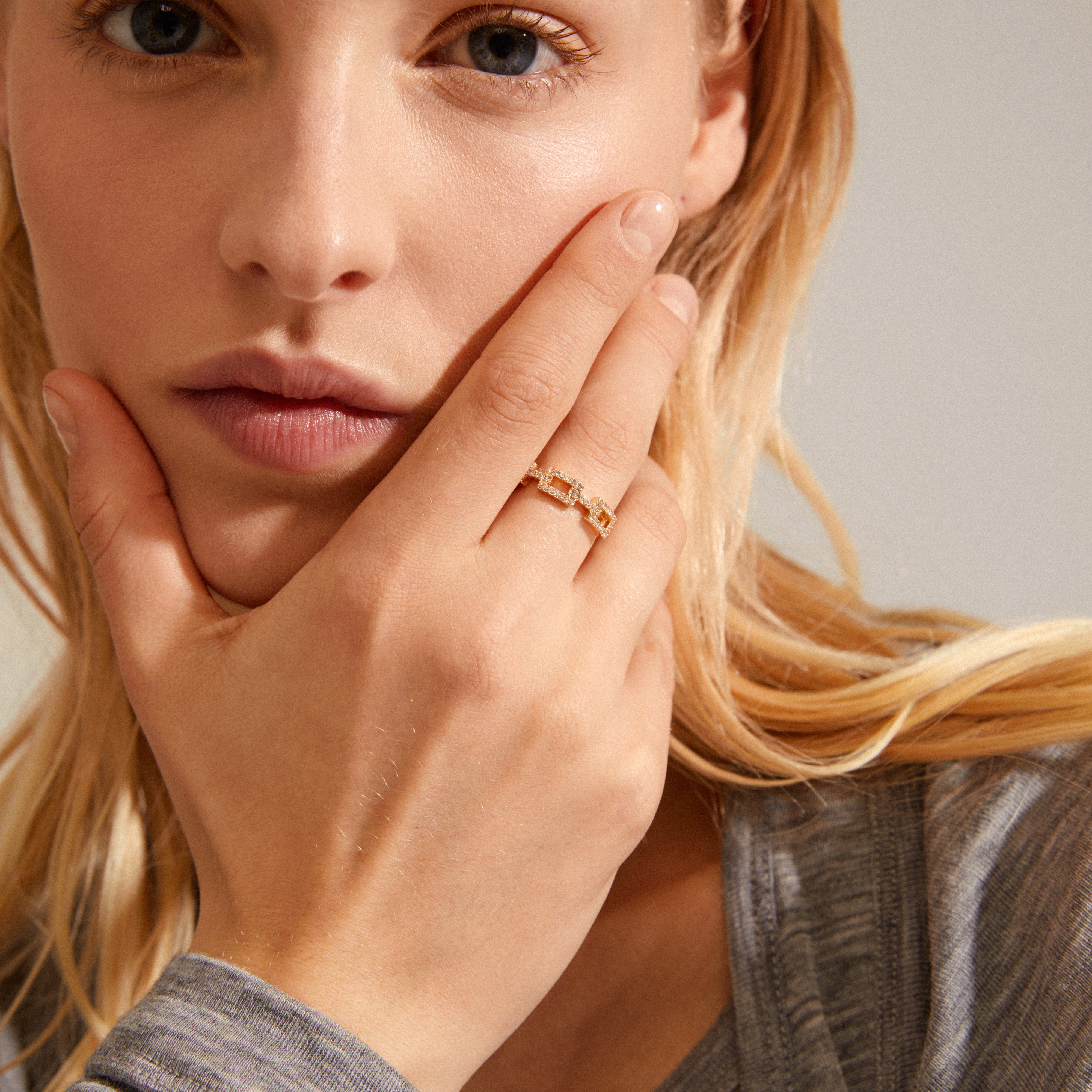 COBY crystal ring gold-plated with rectangular links and sparkling Preciosa crystals, showcased on a woman's hand near her cheek.