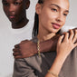 AMIRI bracelet gold-plated with sparkling Preciosa crystals, showcasing an open, fluid design on a wrist, emphasizing its genderless, urban style.