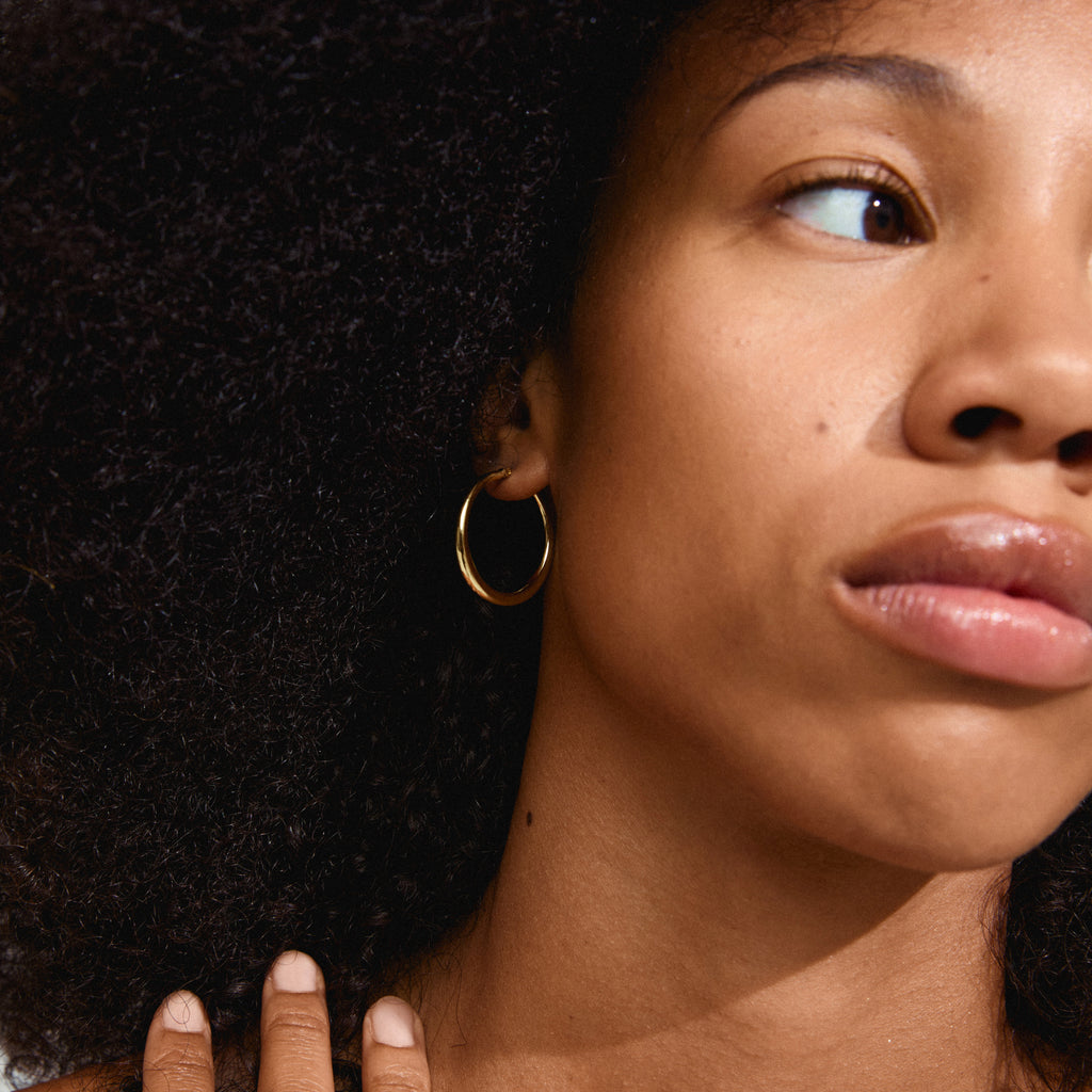 Close-up of a woman wearing gold-plated JORUN hoop earrings, showcasing their timeless elegance and classic 30mm design. Perfect for any occasion.