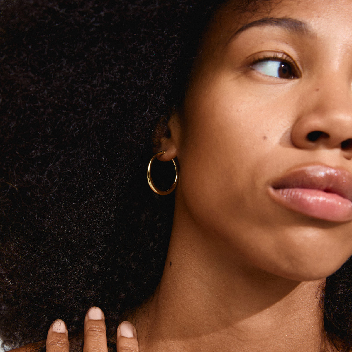 Close-up of a woman wearing gold-plated JORUN hoop earrings, showcasing their timeless elegance and classic 30mm design. Perfect for any occasion.