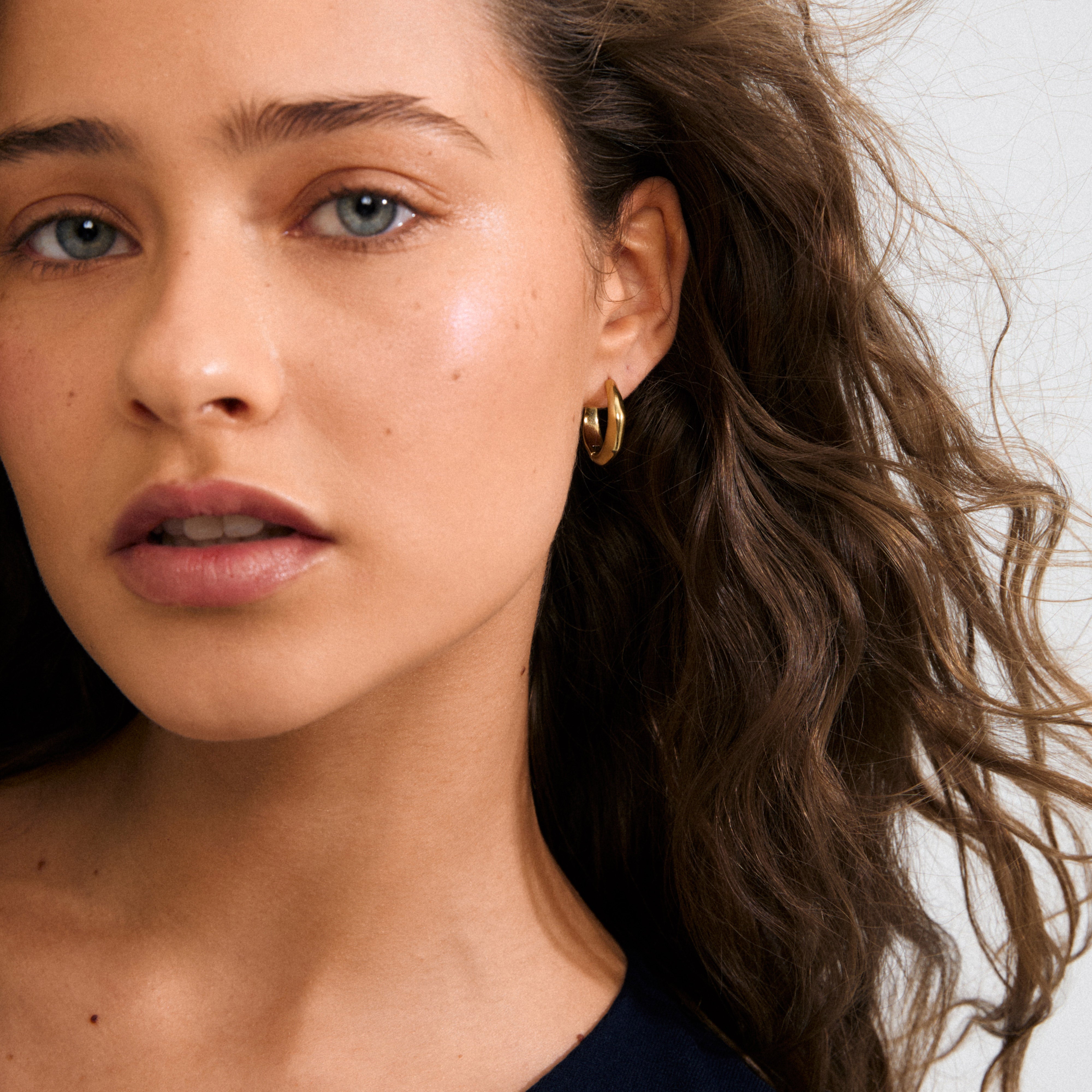 Gold-plated HARRISON hoops with wavy shapes, offering a luxurious Scandinavian design. Waterproof and eco-friendly, perfect for everyday stylish wear.