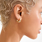 Person wearing JENNINGS gold-plated mini hoop earrings, showcasing their chunky, sculptural design that closely hugs the earlobe for a chic, effortless look.