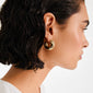 Side profile close-up showcasing a JENNINGS gold-plated hoop earring by Pilgrim. The chunky design hugs the ear, offering a bold, sculptural look.