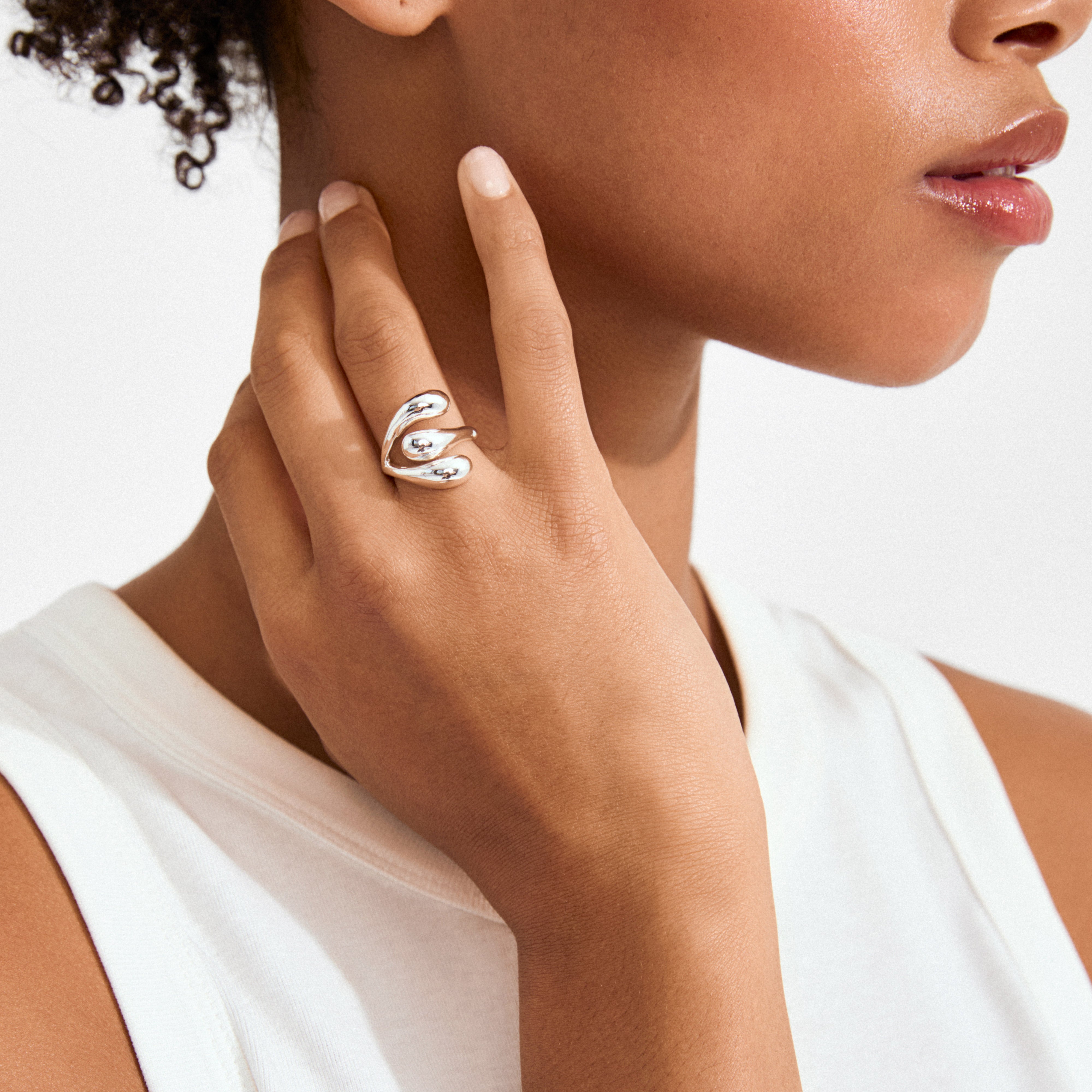 JENNINGS ring silver-plated on finger; sculptural, droplet-like ends wrap elegantly, showcasing its liquid silver design against a white sleeveless top.