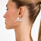 Side profile of a person wearing JENNINGS silver-plated hoop earrings from Pilgrim, showcasing a chunky, sculptural design that hugs the ear boldly. Crafted from recycled materials.