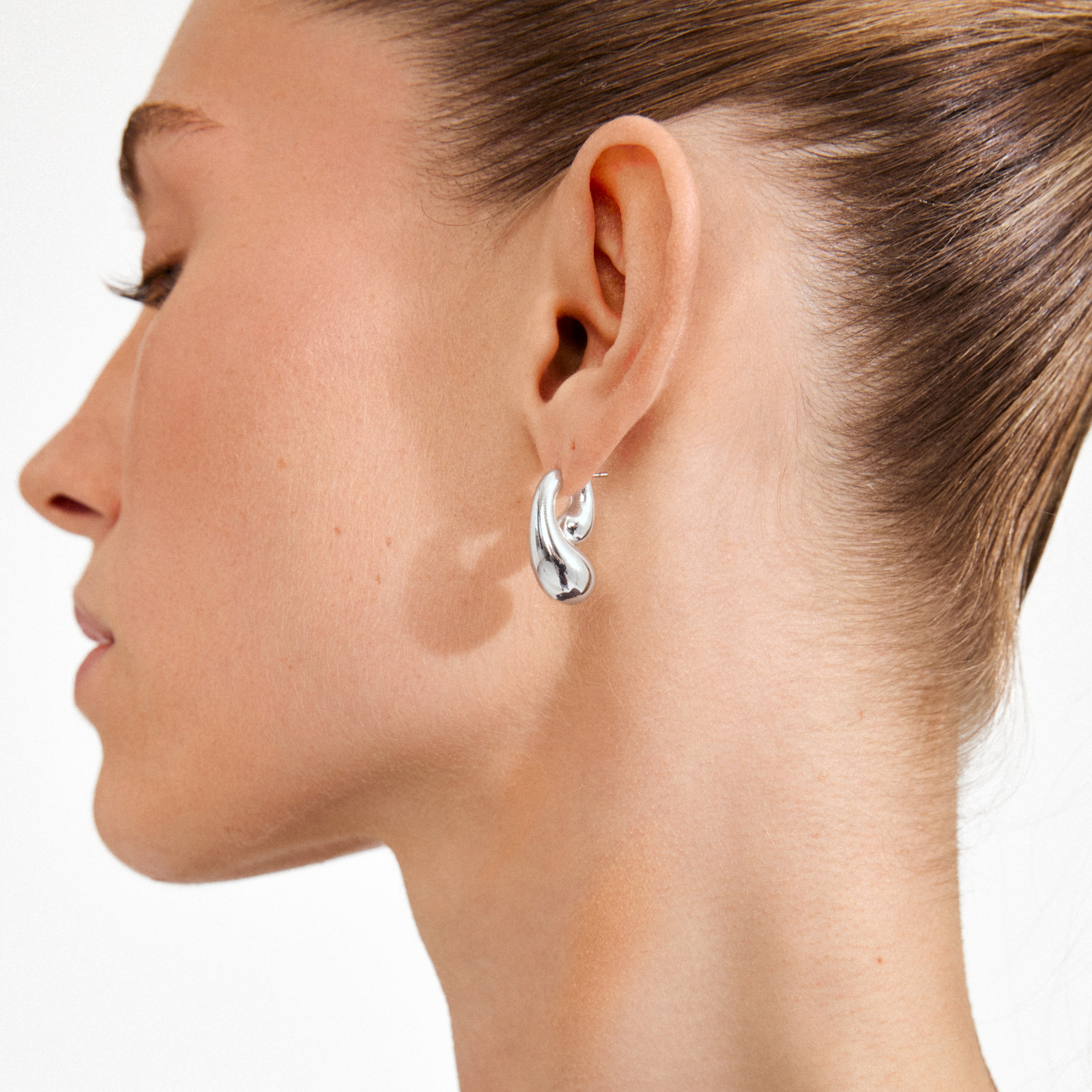 JENNINGS earrings silver-plated by Pilgrim, featuring sculptural, liquid-metal drop design, elegantly wrap around the ear for a modern, standout style.
