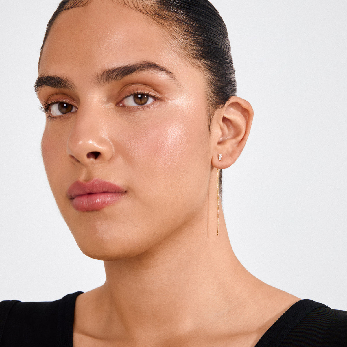 Young woman wearing TITIANA crystal earrings gold-plated; three Preciosa crystals and a delicate chain add elegance and movement to her look.