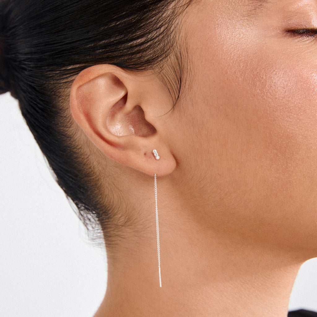 TITIANA crystal earrings silver-plated, featuring delicate chain and vertical Preciosa crystals, elegantly adorn the earlobe, complementing a pulled-back hairstyle for a chic, modern look.