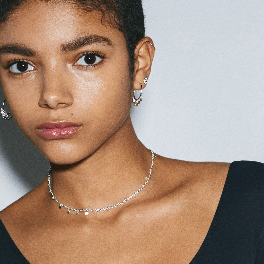 PANNA coin necklace silver-plated on woman’s neck, showcasing delicate round pendants, complementing her earrings.