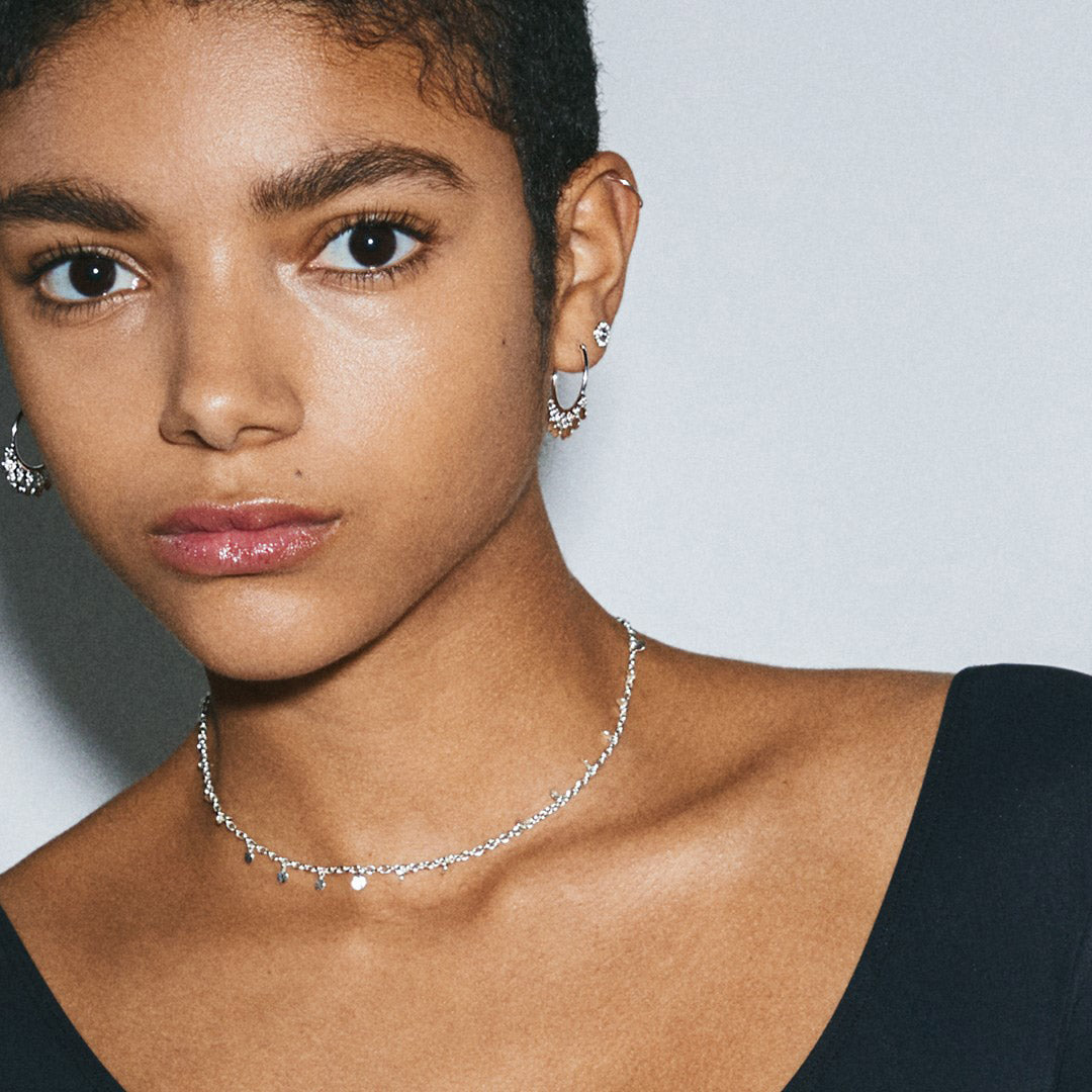 PANNA coin necklace silver-plated on woman’s neck, showcasing delicate round pendants, complementing her earrings.