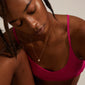 Woman wearing a pink sports garment and the TINA crystal pendant necklace, gold-plated, featuring a delicate chain with an organic, asymmetrical pendant and Preciosa crystal.