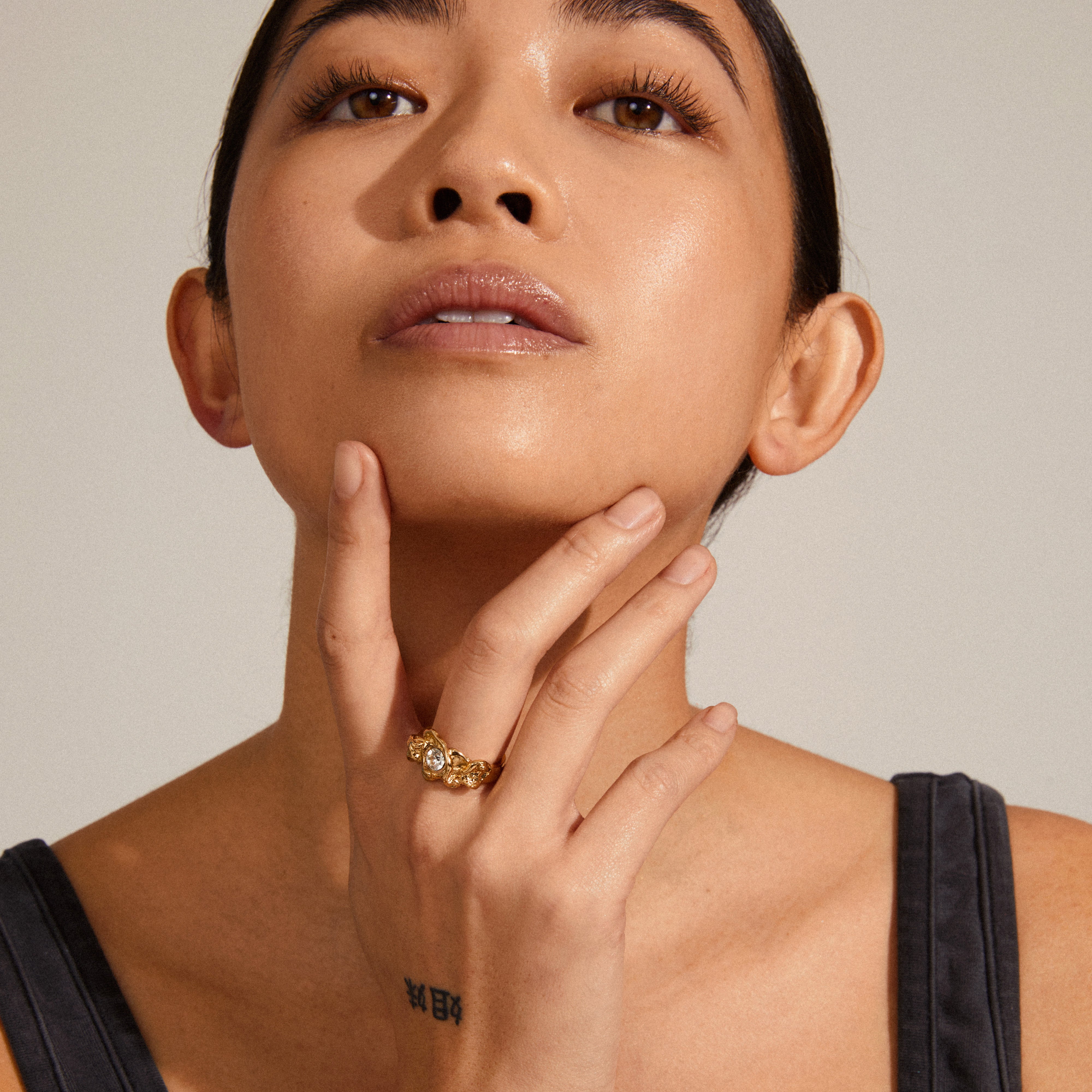 Close-up of a woman wearing the TINA organic shape crystal ring, gold-plated, highlighting its nature-inspired design with a prominent central crystal.