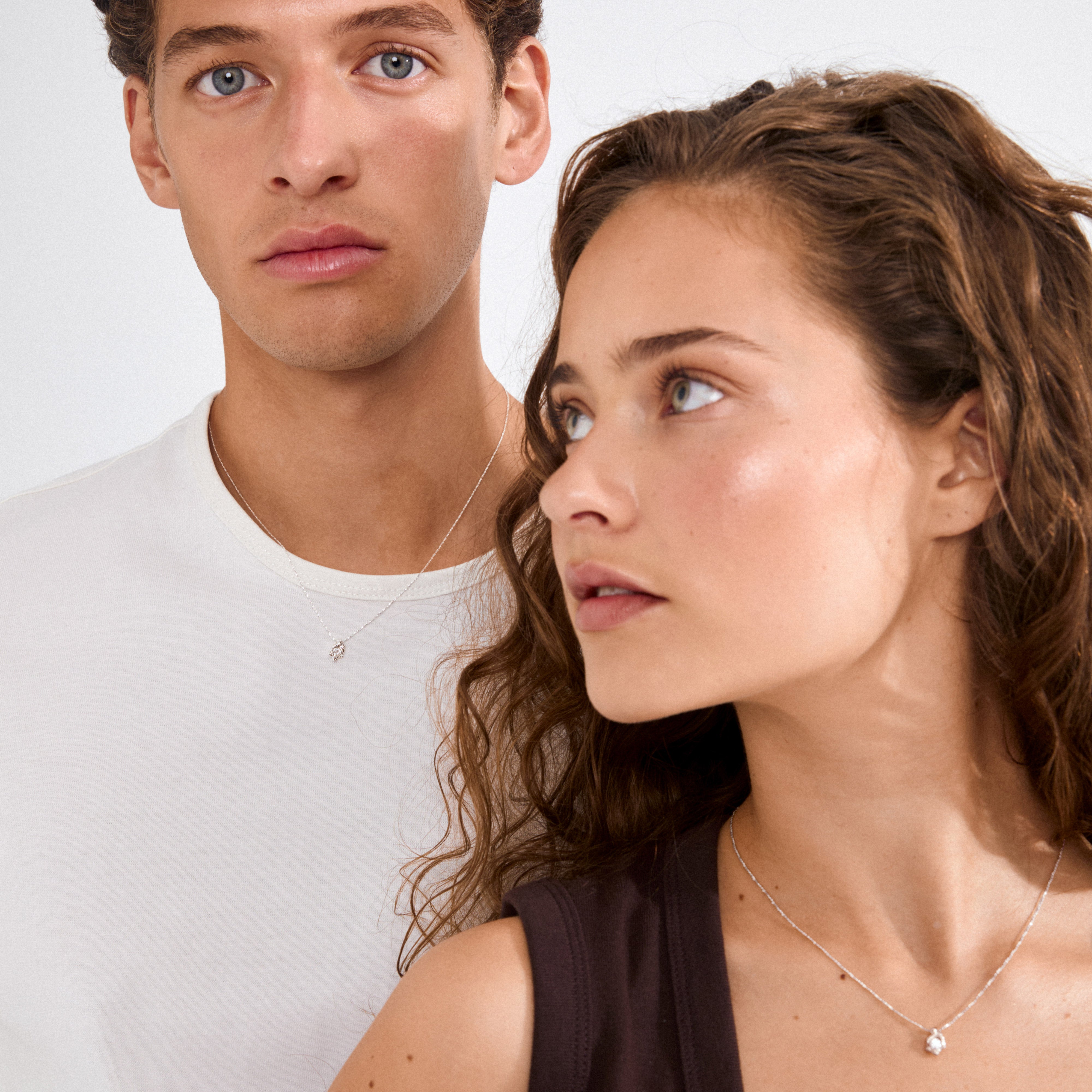 Two young adults model the TINA crystal pendant necklace, silver-plated, showcasing its elegant, nature-inspired design and adjustable chain for perfect fit.