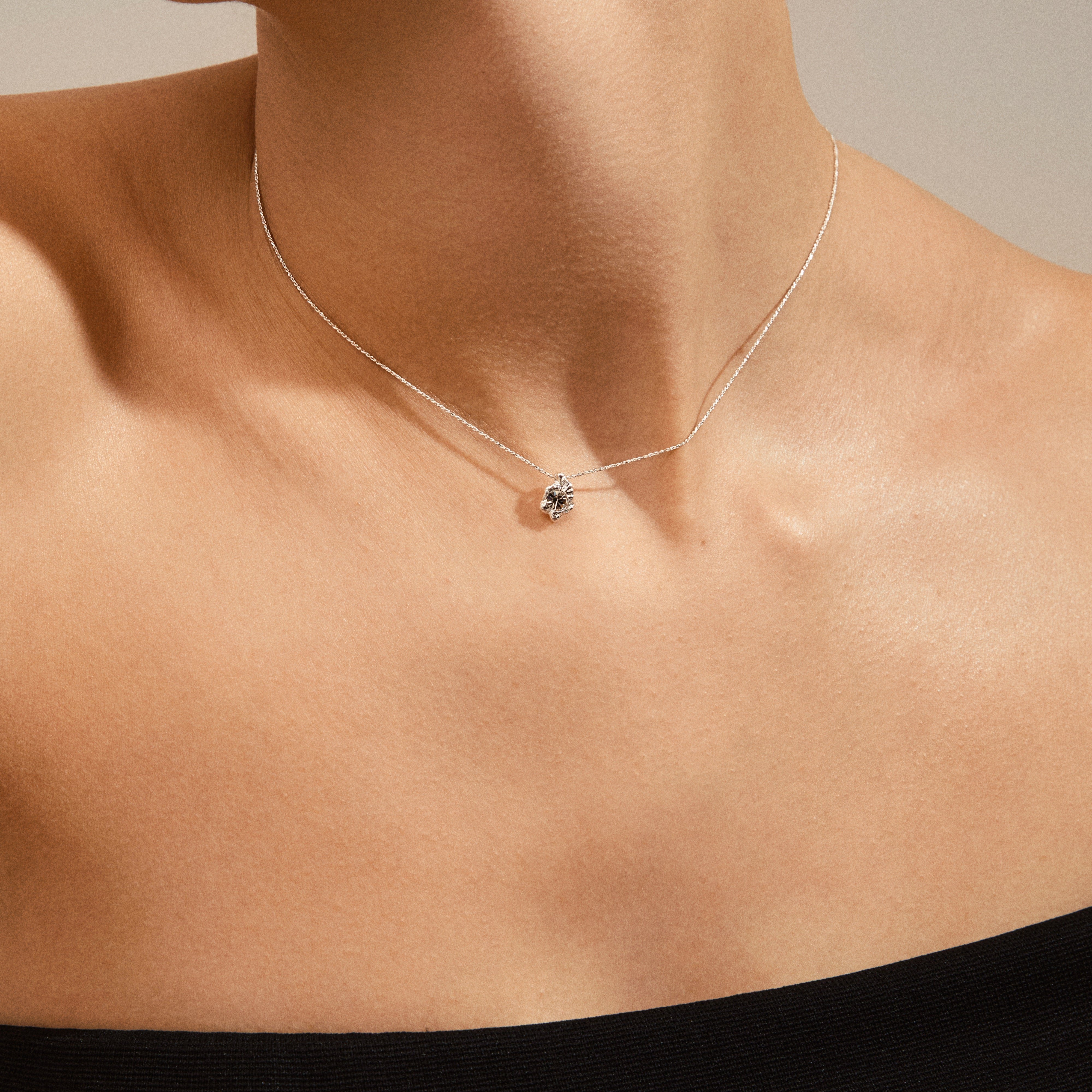 TINA crystal pendant necklace silver-plated on a neck, showcasing its organic, irregular design, inspired by nature, with a subtle shine on a fine silver chain.