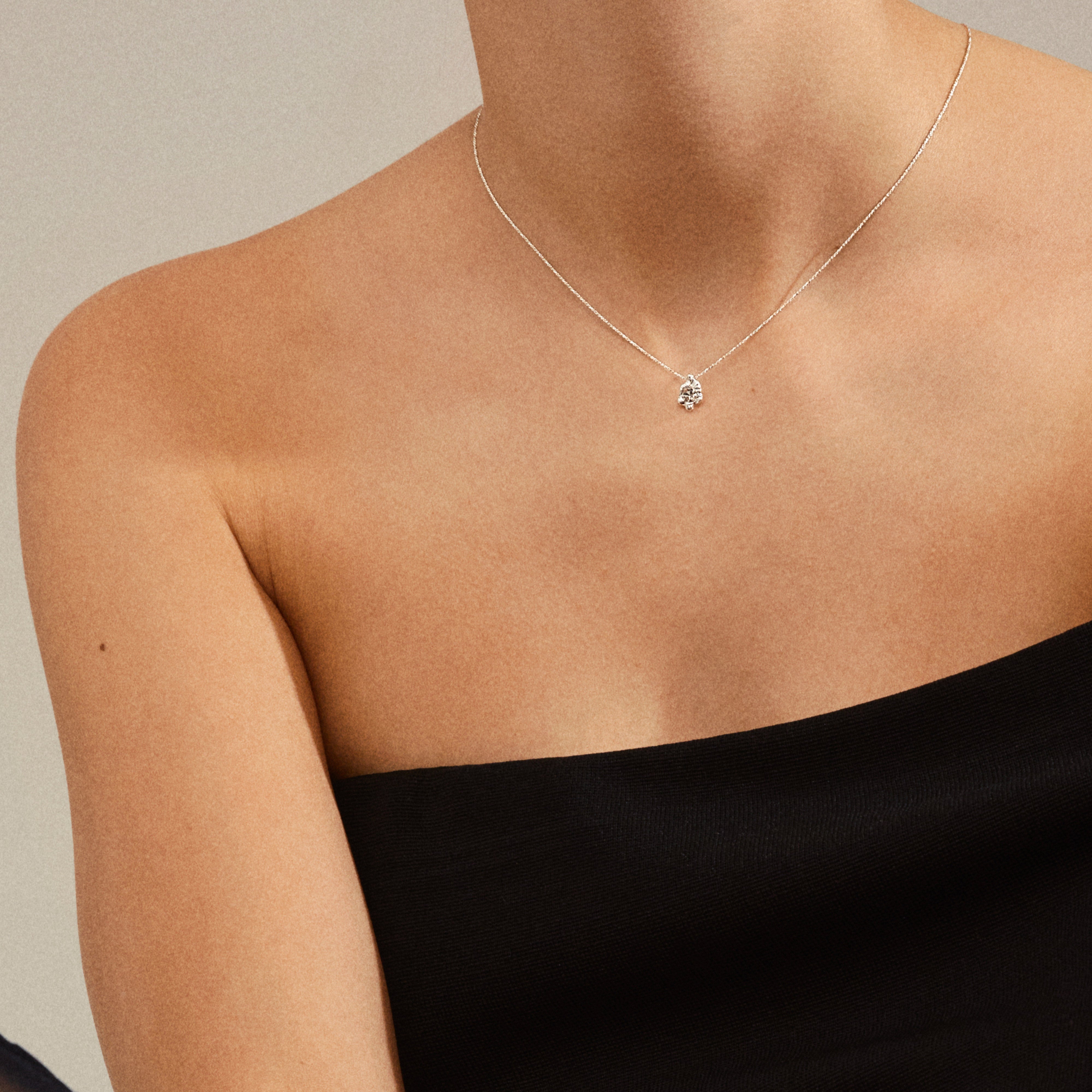 Close-up of a person wearing the TINA crystal pendant necklace, silver-plated, featuring a small floral motif on a fine chain.