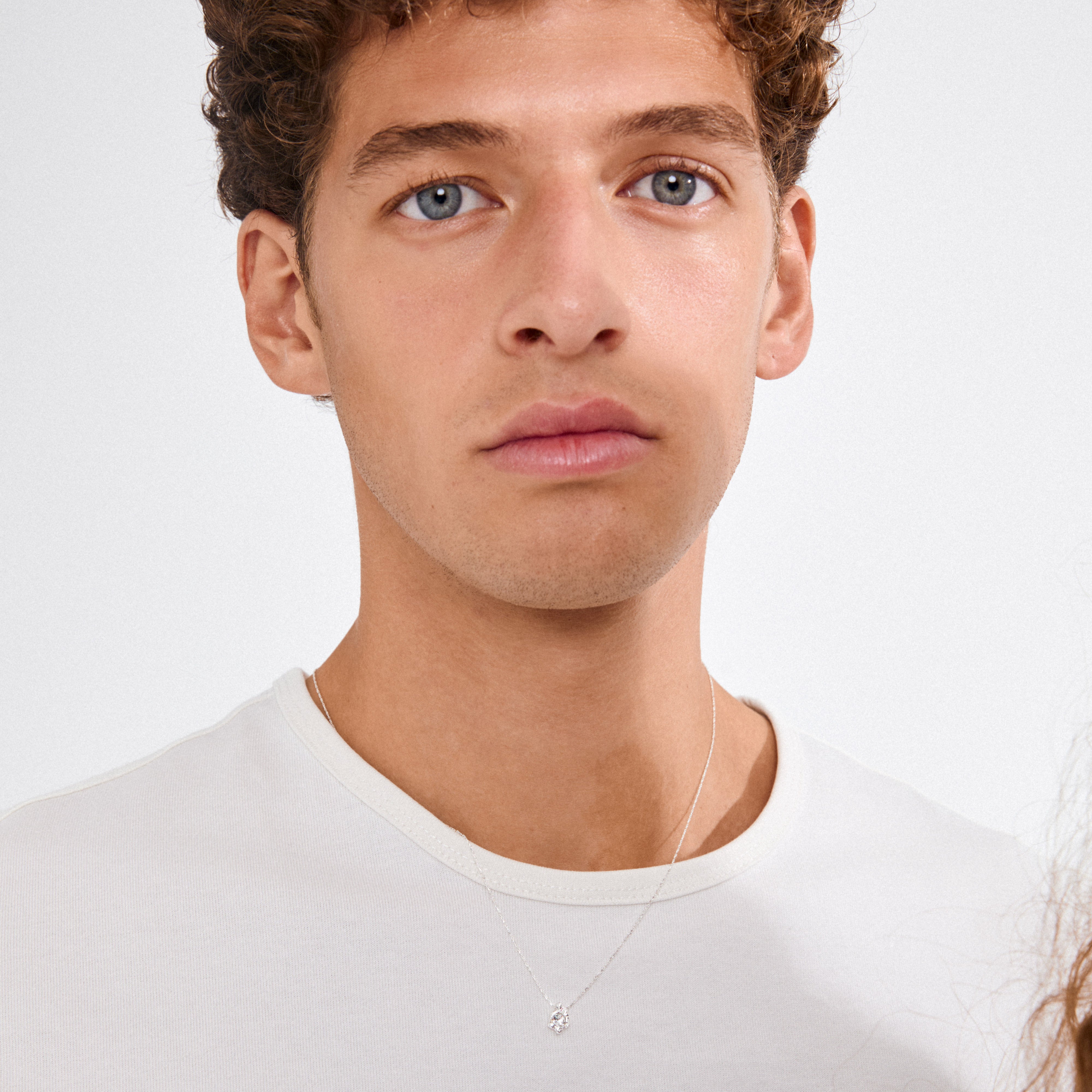 Young man wearing the TINA crystal pendant necklace, silver-plated with a wavy, sculptural design, showcasing its elegant simplicity and chic style.