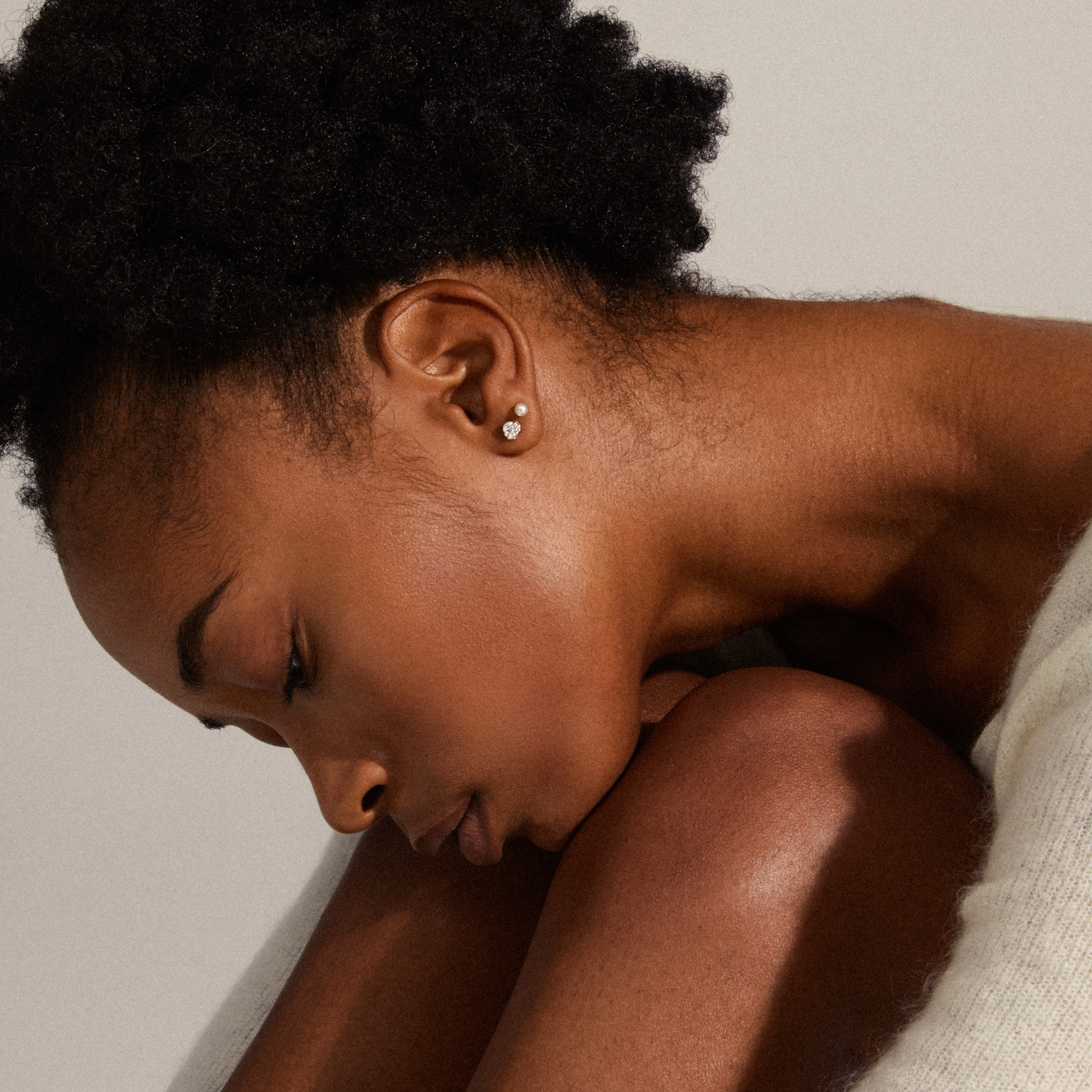 TINA crystal & pearl studs, silver-plated, showcased on a woman with closed eyes, highlighting the ear's elegance in a trendy, minimalist style.