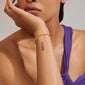 Woman wearing sunglasses and showcasing a tattooed arm, highlighting the HALLIE organic shaped crystal bracelet gold-plated from Pilgrim's Hallie series, featuring asymmetric design and cool chain details.