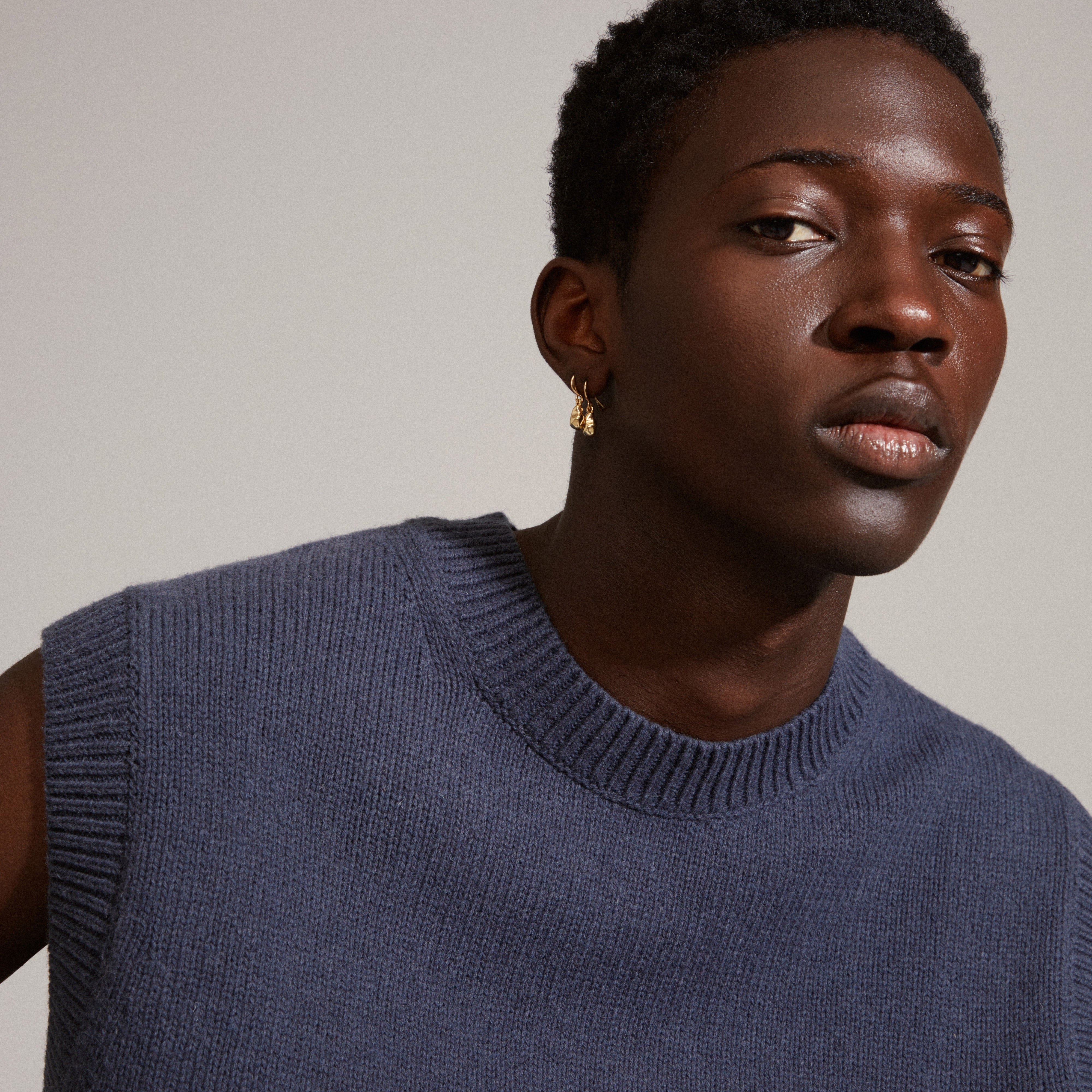 Close-up of a man wearing CHANTAL earrings, gold-plated with organic shapes, highlighting Pilgrim's handcrafted, recycled design.