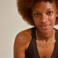 Woman wearing RIKO necklaces, 2-in-1 set from Pilgrim, featuring a gold-plated layered design with a curb chain and nature-inspired pendants.