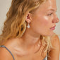 RIKO earrings silver-plated: Close-up of a woman wearing nature-inspired, flower-pendant silver earrings from Pilgrim's RIKO series, showcasing their summery, recycled, and creative design.