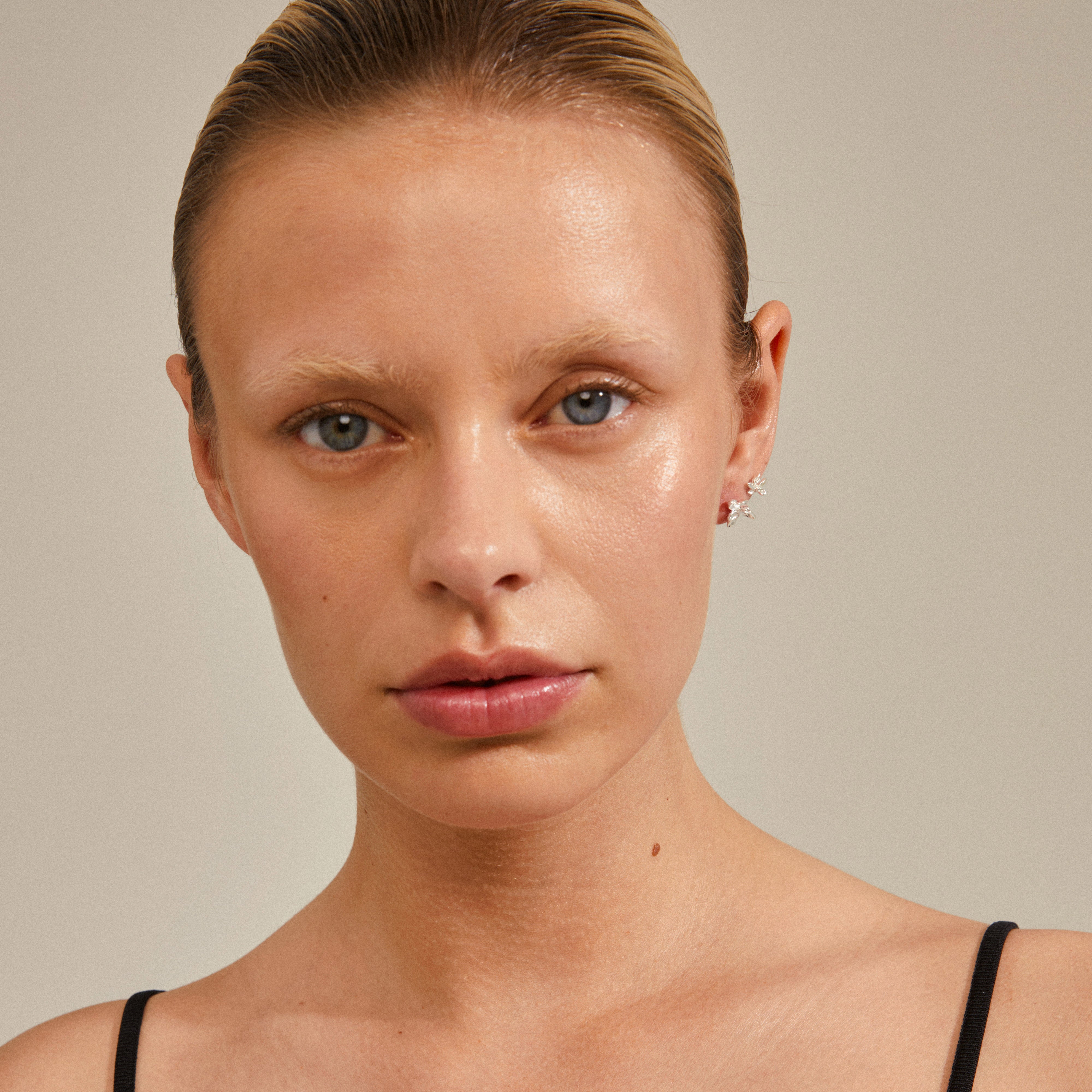 Close-up of a woman wearing Pilgrim's RIKO earrings, a 2-in-1 silver-plated set, featuring unique, organically inspired shapes.