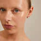 Close-up of a woman wearing RIKO earrings, a 2-in-1 silver-plated set by Pilgrim, showcasing their unique, nature-inspired organic shapes.
