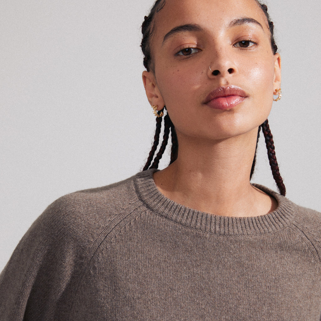ZHURI earrings 2-in-1 set gold-plated, worn by a woman with braids, featuring floral half-hoops and studs from Pilgrim's sustainable collection.