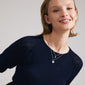 Woman smiling, wearing Pilgrim's ZHURI necklace 2-in-1 set, featuring a silver-plated flower pendant and freshwater pearl for an effortless romantic style.