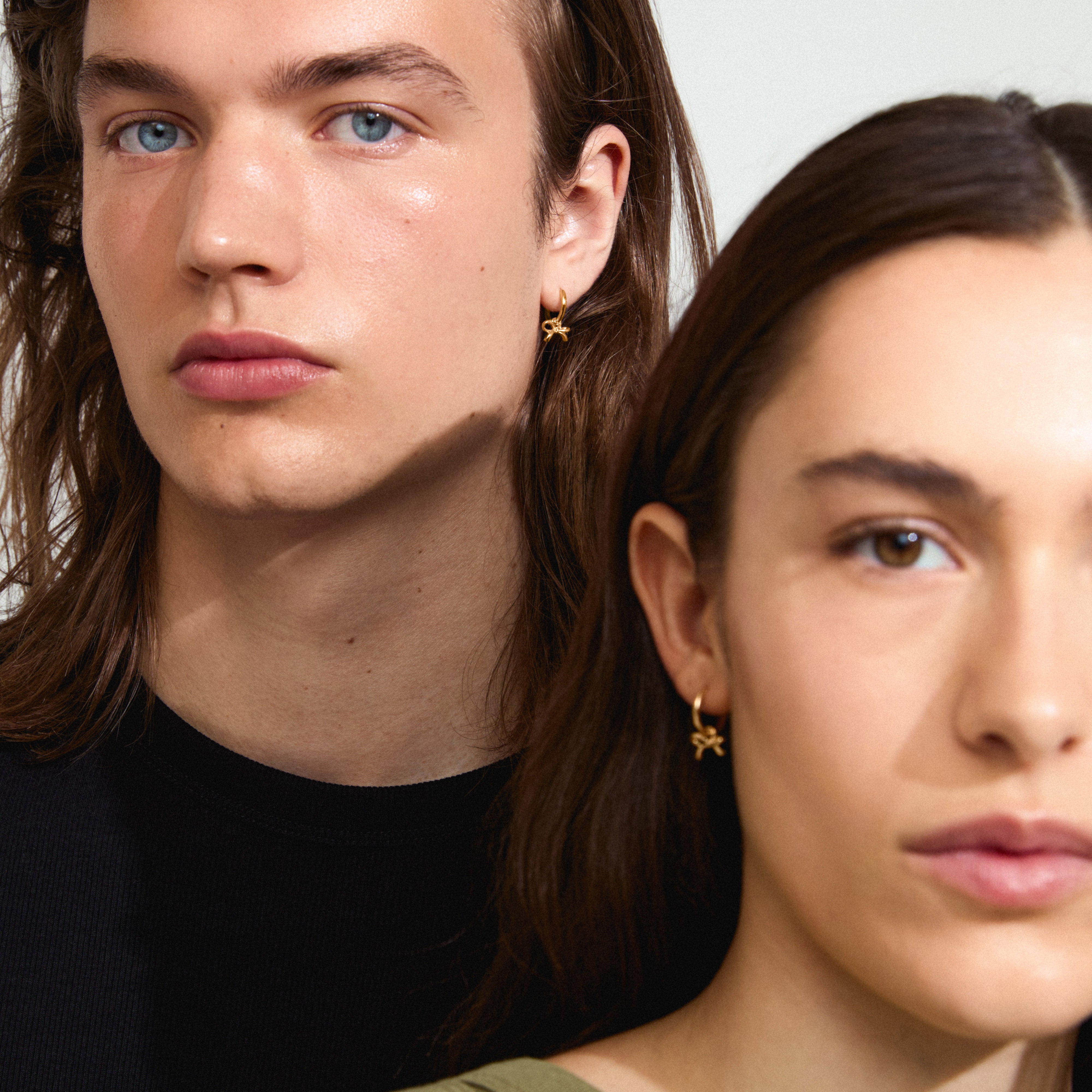 LYSANDRA hoop earrings gold-plated: A man and woman showcasing Pilgrim's gold-plated bow earrings, highlighting their elegant design and eco-friendly craftsmanship. Perfect for elevating summer fashion.