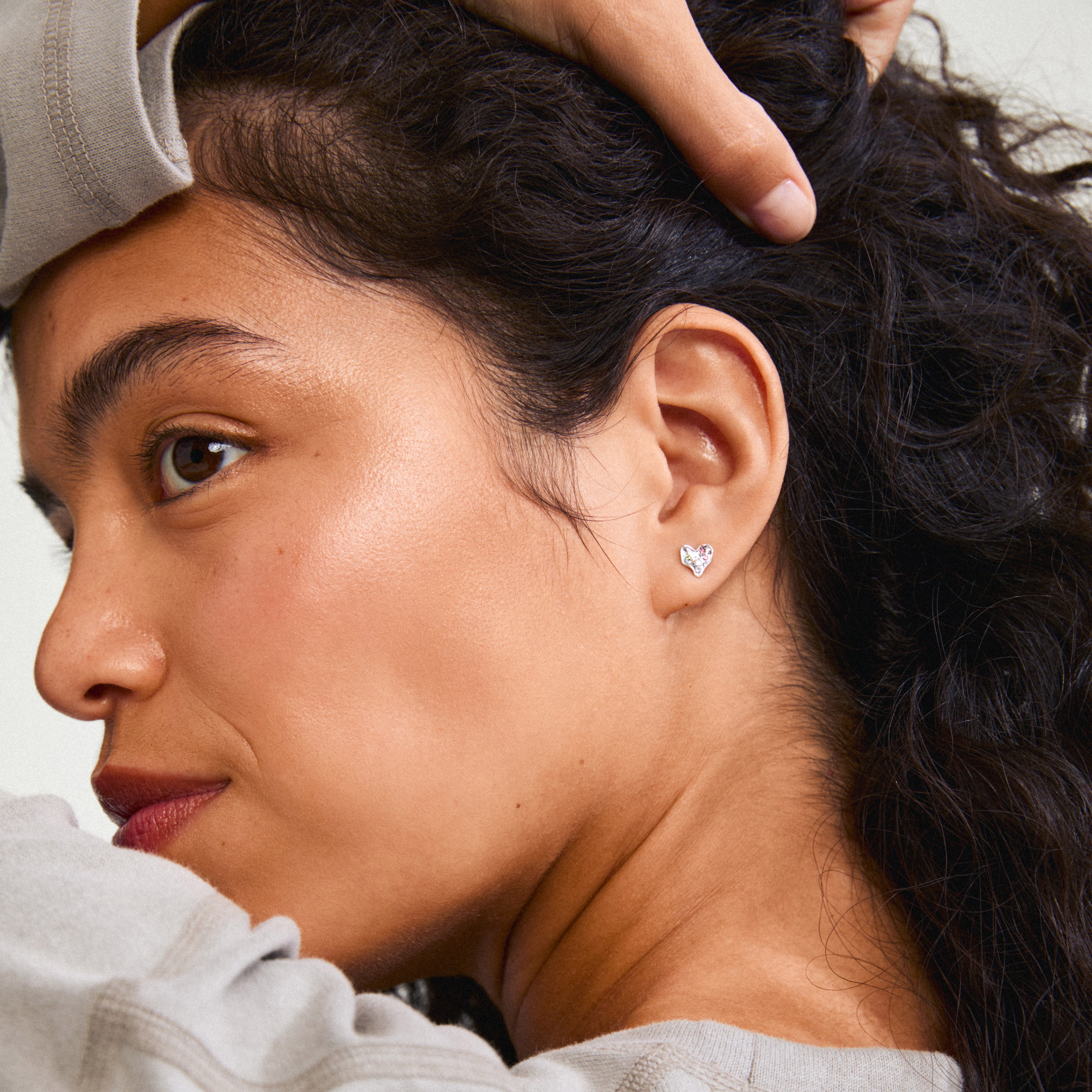 RYAN heart earrings silver-plated, featuring organic heart shapes with Preciosa crystals, worn by a woman touching her head, showcasing Pilgrim's handmade elegance.