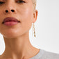 Close-up of a person's ear wearing ELIYAH gold-plated chain earrings by Pilgrim, showcasing textured curb links and sculptural design for stylish, sustainable flair.